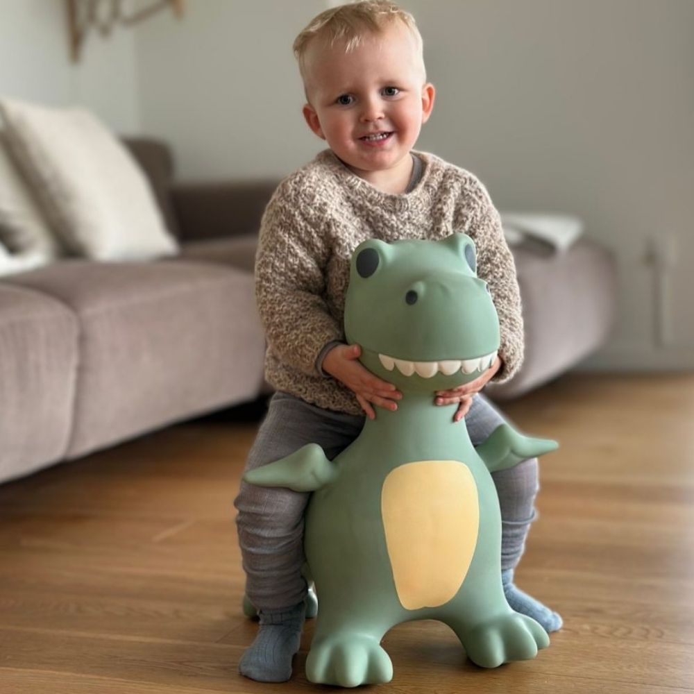 dreng sidder på støvet grøn dino hoppedyr i stue, hoppedyrfra Find that Hippo fås hos Nordic Simply