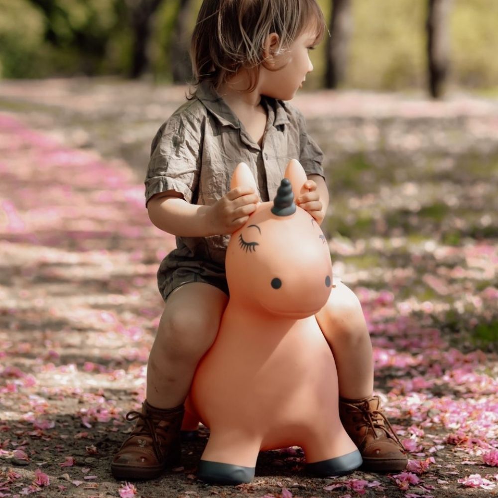 barn rider på rosa enhjørning hoppedyr fra Find That Hippo udendørs i skovbund med rosa blade, fås hos Nordic Simply