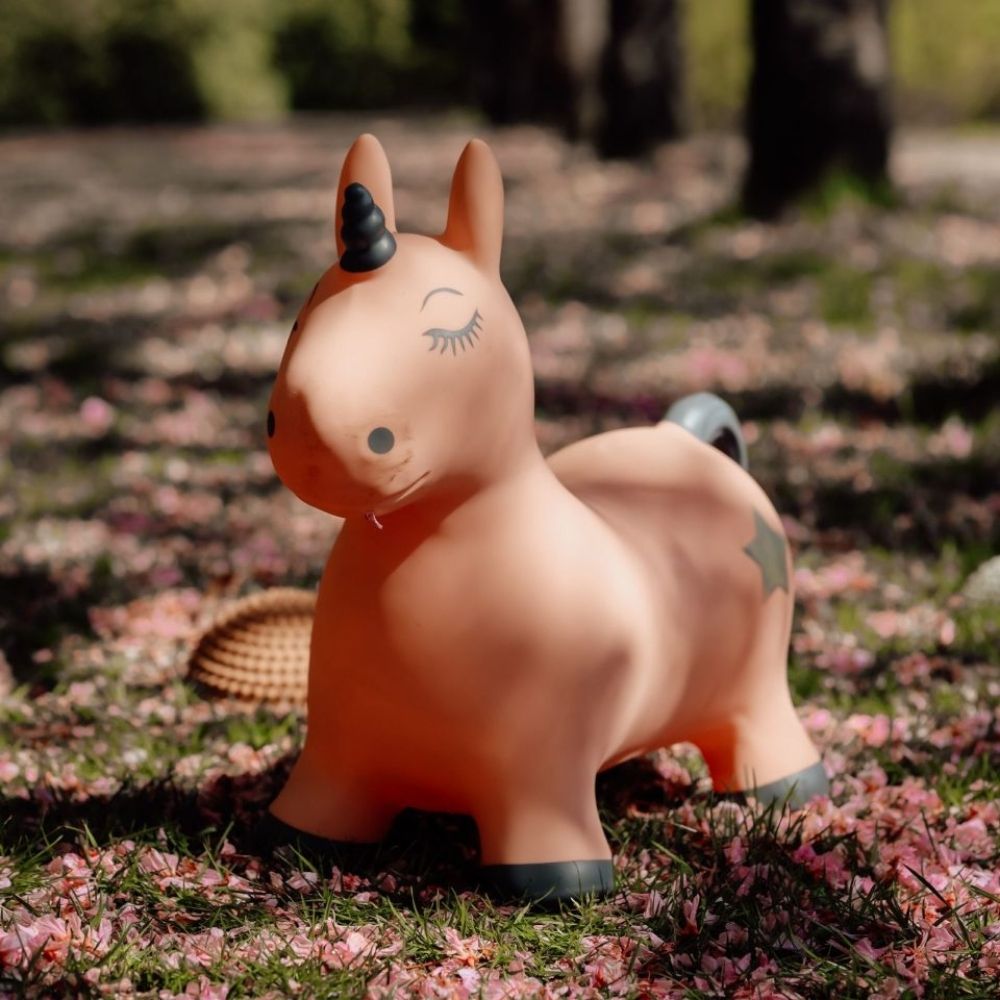 rosa enhjørning hoppedyr fra Find That Hippo står udendørs i skovbund med rosa blade, fås hos Nordic Simply