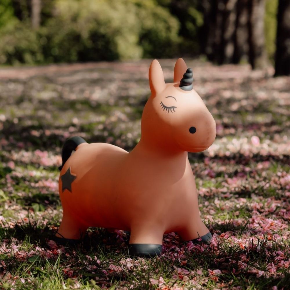 rosa enhjørning hoppedyr fra Find That Hippo står udendørs i skovbund med rosa blade, fås hos Nordic Simply