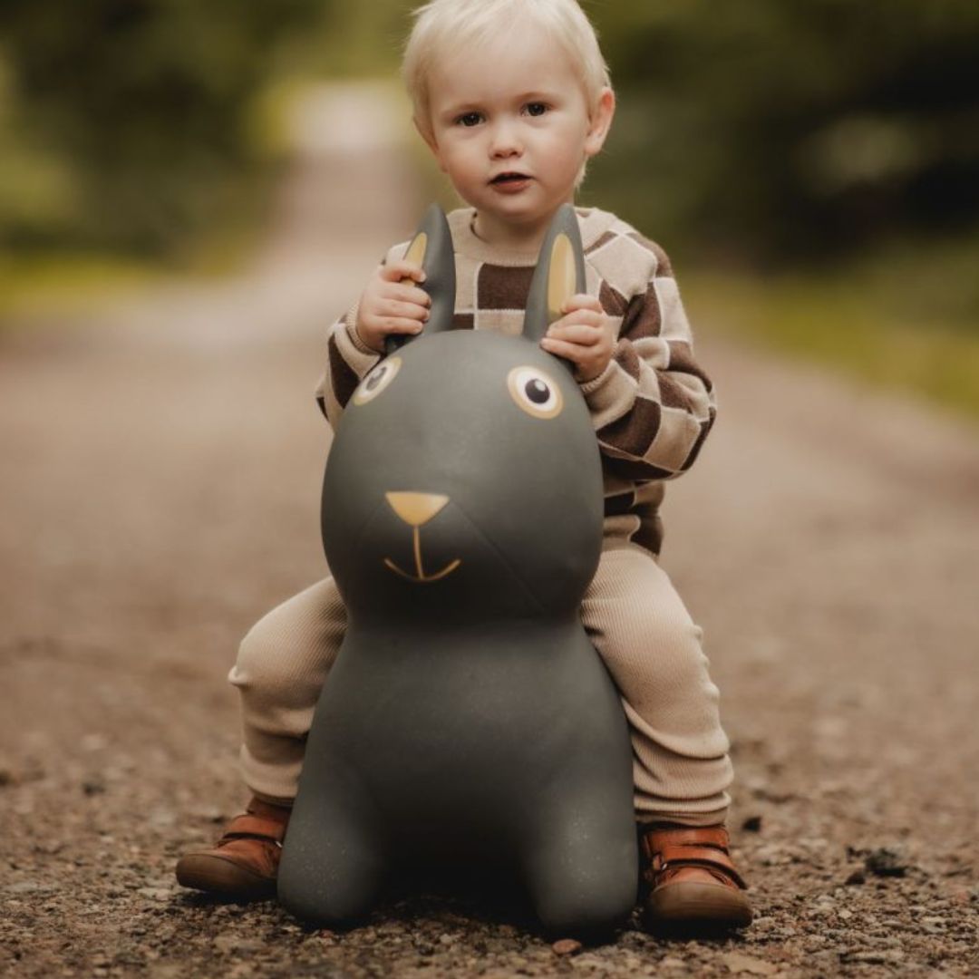 Barn, der rider på sjovt grå kanin hoppedyr med store ører, træner motorik og balance, perfekt til børn fra 2 år.