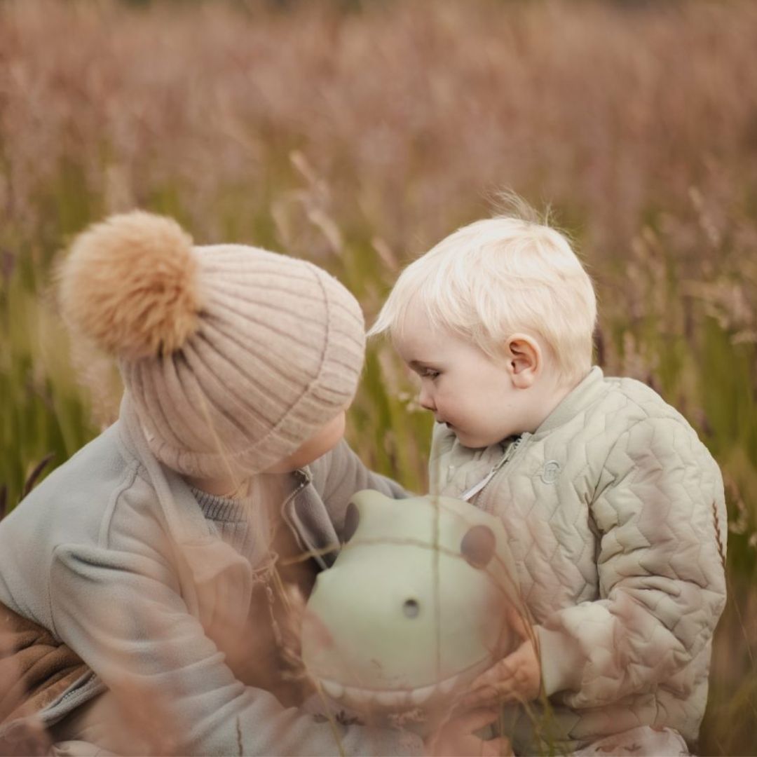 børn i eng med støvet grøn dino hoppedyr imellem sig, legetøj til aktiv inde og udeleg fra Find that Hippo fås hos Nordic Simply