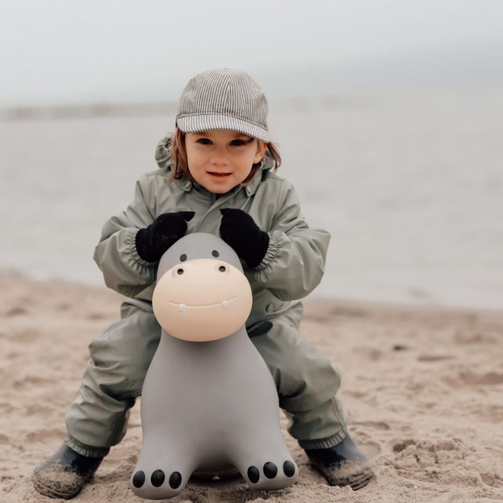 Barn leger på grå flodhest hoppedyr, træner balance og koordination på stranden.