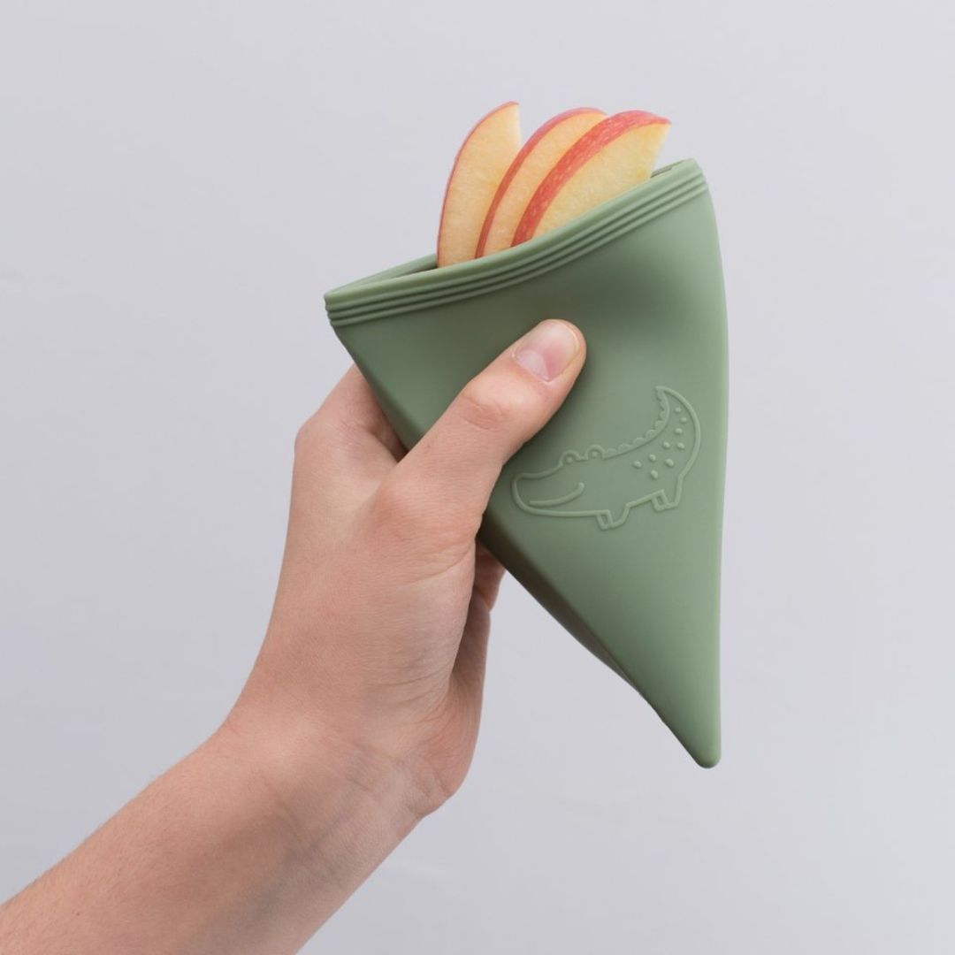 Hånd holder trekantet grøn isform med skiver af æbler i, trekant isforme til at lave is, eller opbevare snacks, fra We Might Be Tiny, fås hos Nordic Simply