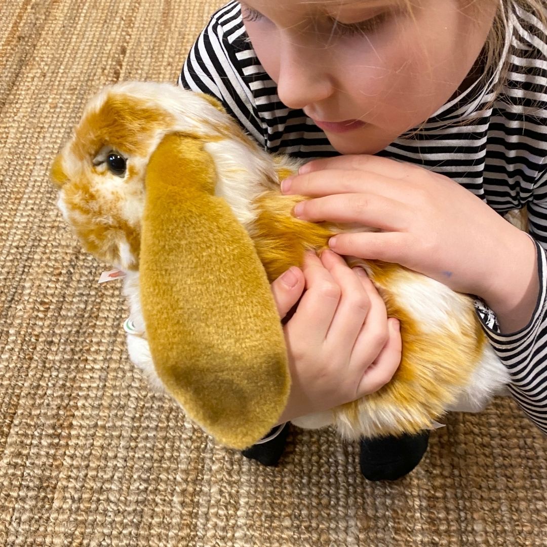 Barn holder brun-hvid vædder kanin bamse helt tæt, som ægte kæledyr, perfekt til rolle- og fantasileg, fra Teddy Hermann fås hos Nordic Simply