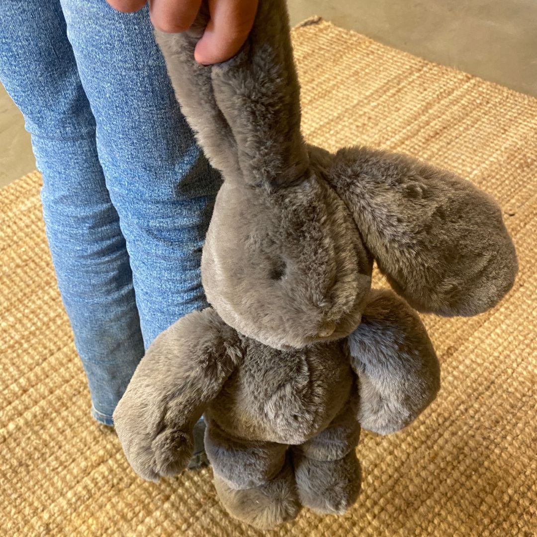 Barn holder grå kaninbamse i øret. Plyskanin med blød øko-tex® certificeret pels fra Moulin Roty, godkendt fra 0 år. Perfekt som barselsgave fås hos Nordic Simply