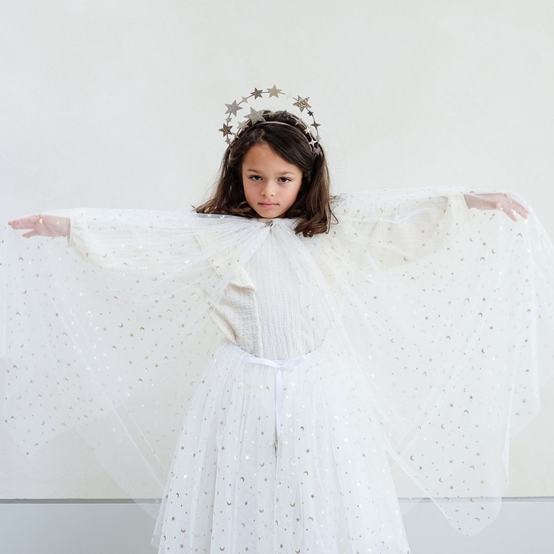 Pige viser lang hvid kappe og tylskort med masser af små guld stjerner, perfekt til udklædning som fe, lucia og prinsesse, fra Mimi & Lula fås hos Nordic Simply