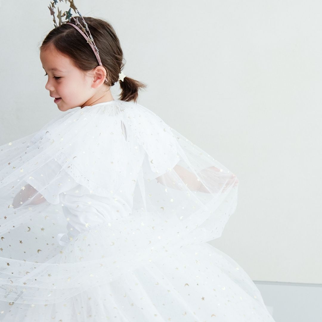 Pige set bagfra i lang hvid kappe og tylskort med masser af små guld stjerner, perfekt til udklædning som fe, lucia og prinsesse, fra Mimi & Lula fås hos Nordic Simply