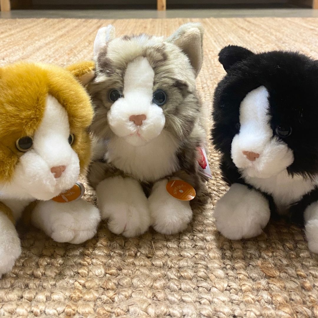 Grå kattebamse, med blå øjne, ligner ægte grå killing, ligger sammen med rød kattekilling bamse ogsort kattekilling bamse, alle fra Teddy Hermann fås hos Nordic Simply