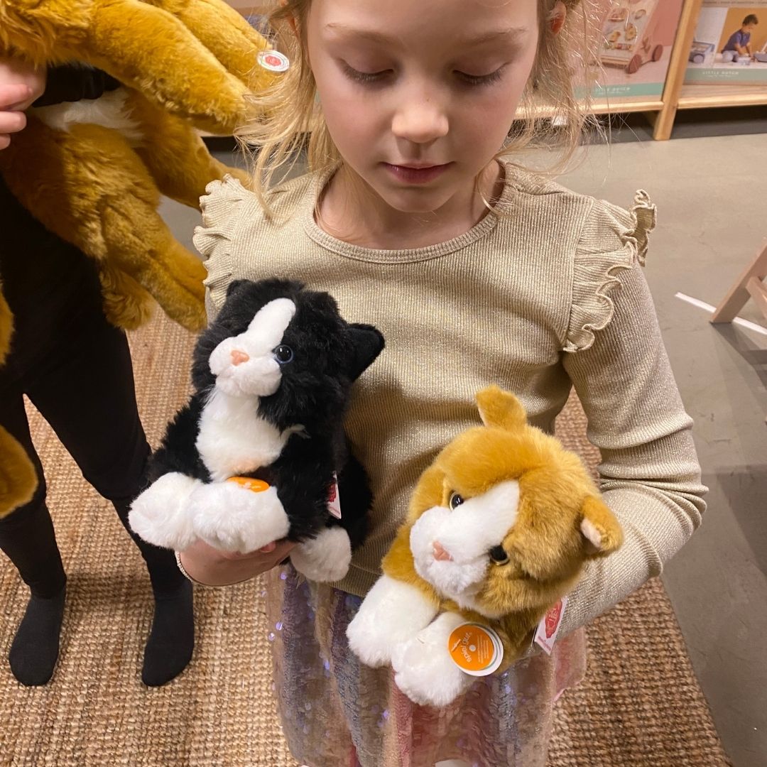 Pige står og holder 2 katte bamser i rød og sort, ligner ægte killinger, fra Teddy Hermann fås hos Nordic Simply