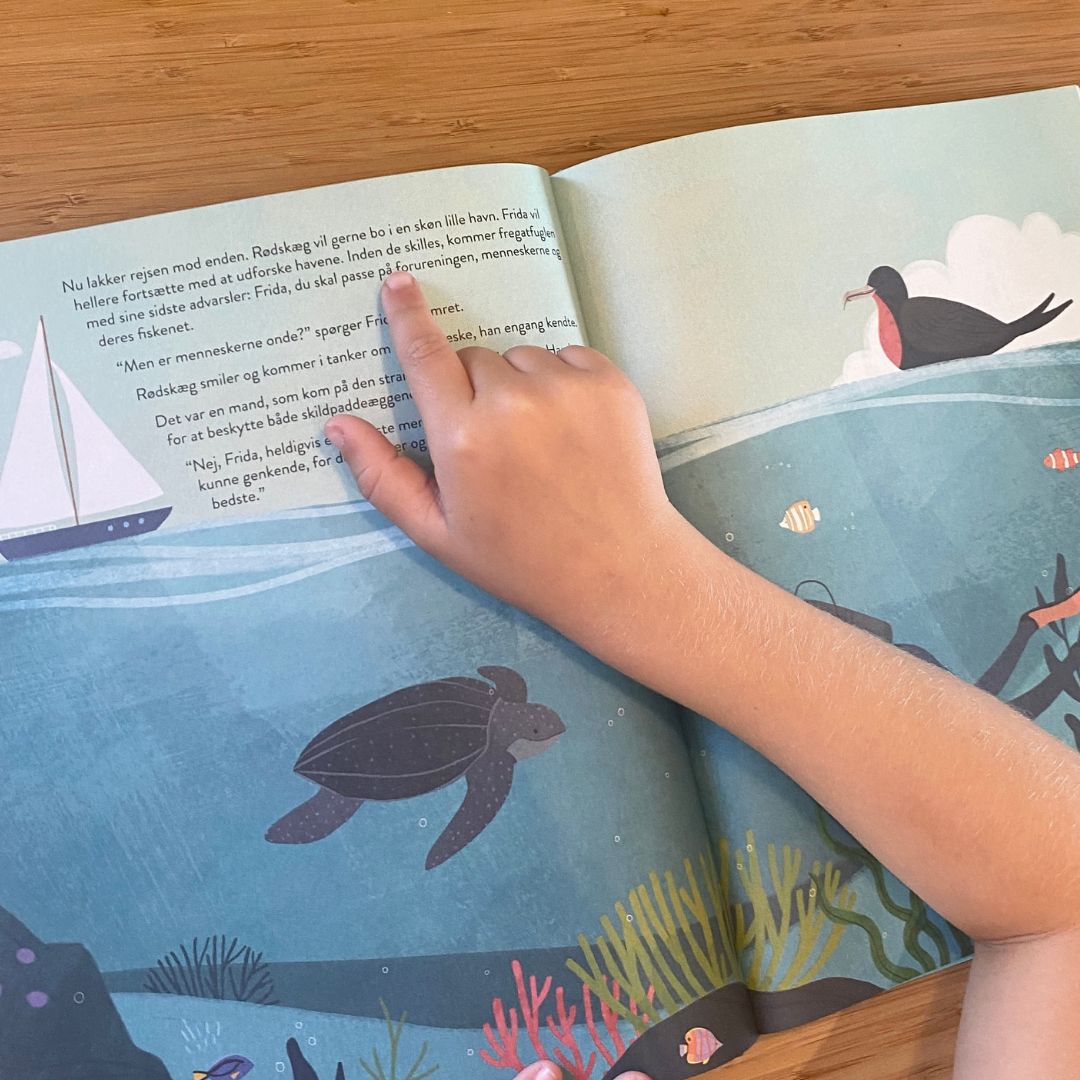 Hånd peger på side i stor klimabog til børn Sådan Passer vi på Jorden, hardback fra Room2Play fås hos Nordic Simply