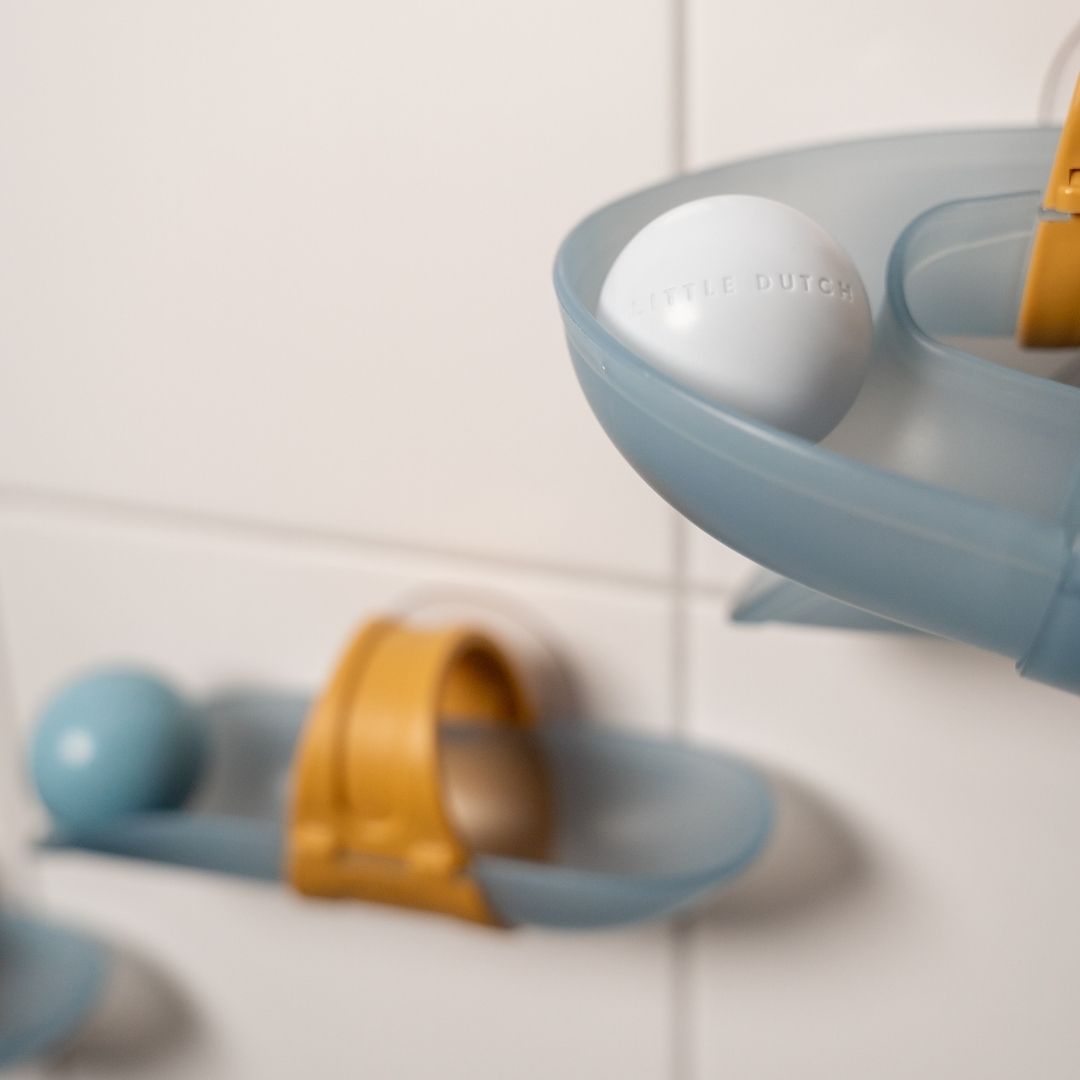 Hvid bold triller nedad blå kuglebane i badet set tæt på på hvide klinker, fra Little Dutch, fås hos Nordic Simply