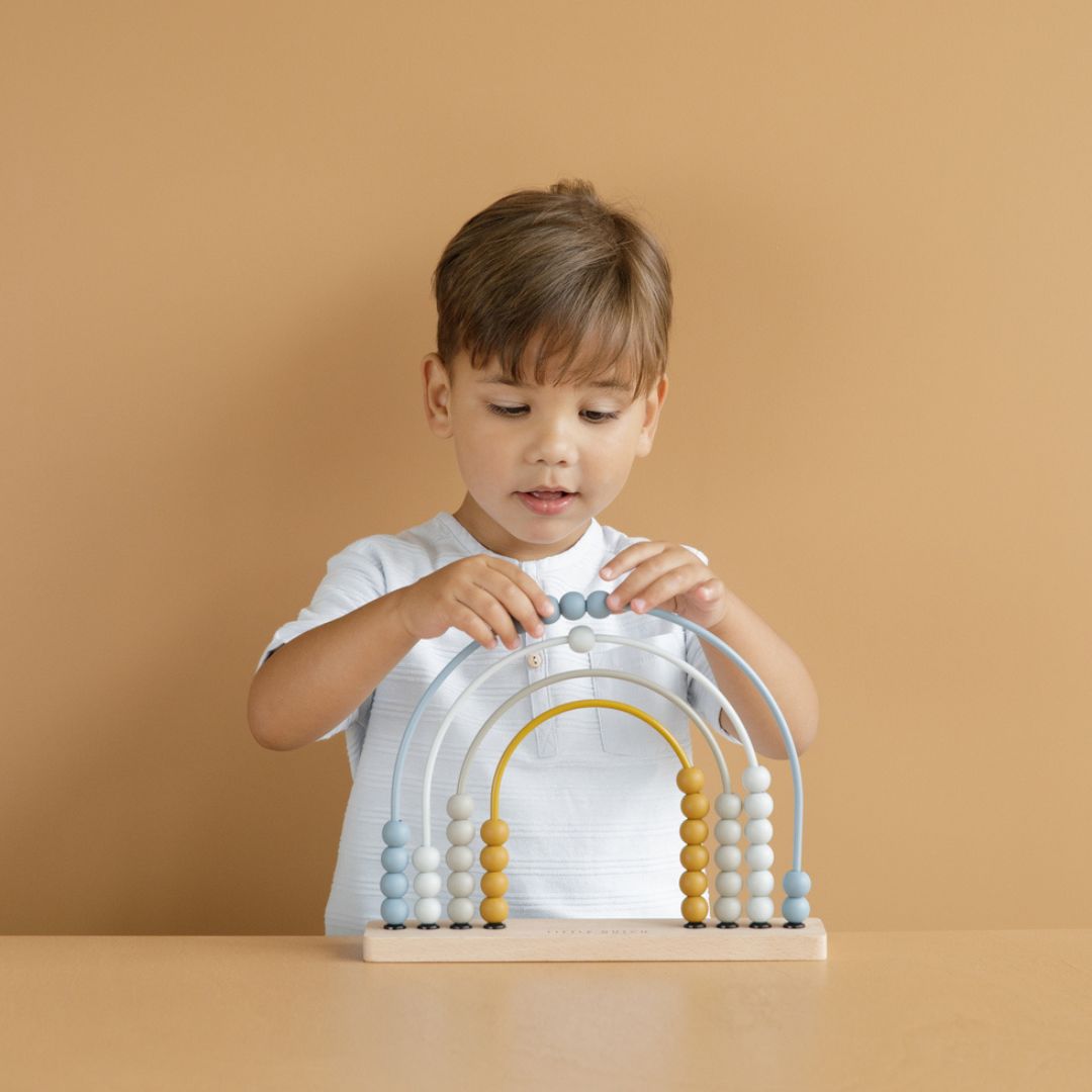 Barn leger med blå regnbue kugleramme med træperler fra Little Dutch, perfekt til læring og udvikling af børns finmotorik.