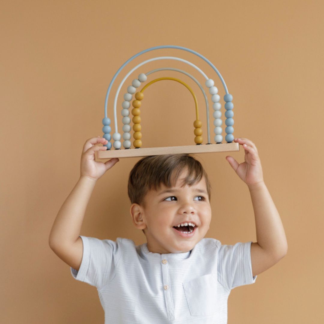 Barn holder blå regnbue kugleramme med træperler fra Little Dutch,på hovedet.