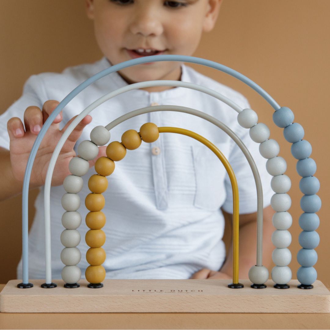 Barn tæller med blå regnbue kugleramme med træperler fra Little Dutch, perfekt til læring og udvikling af børns finmotorik.