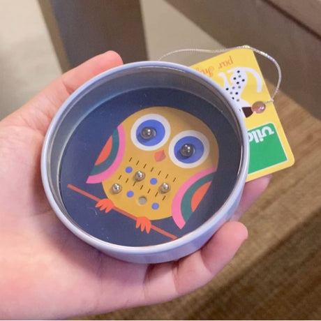 Hånd holder mini kuglespil med ugle i rund æske i klare blå farver fra Vilac, fås hos Nordic Simply