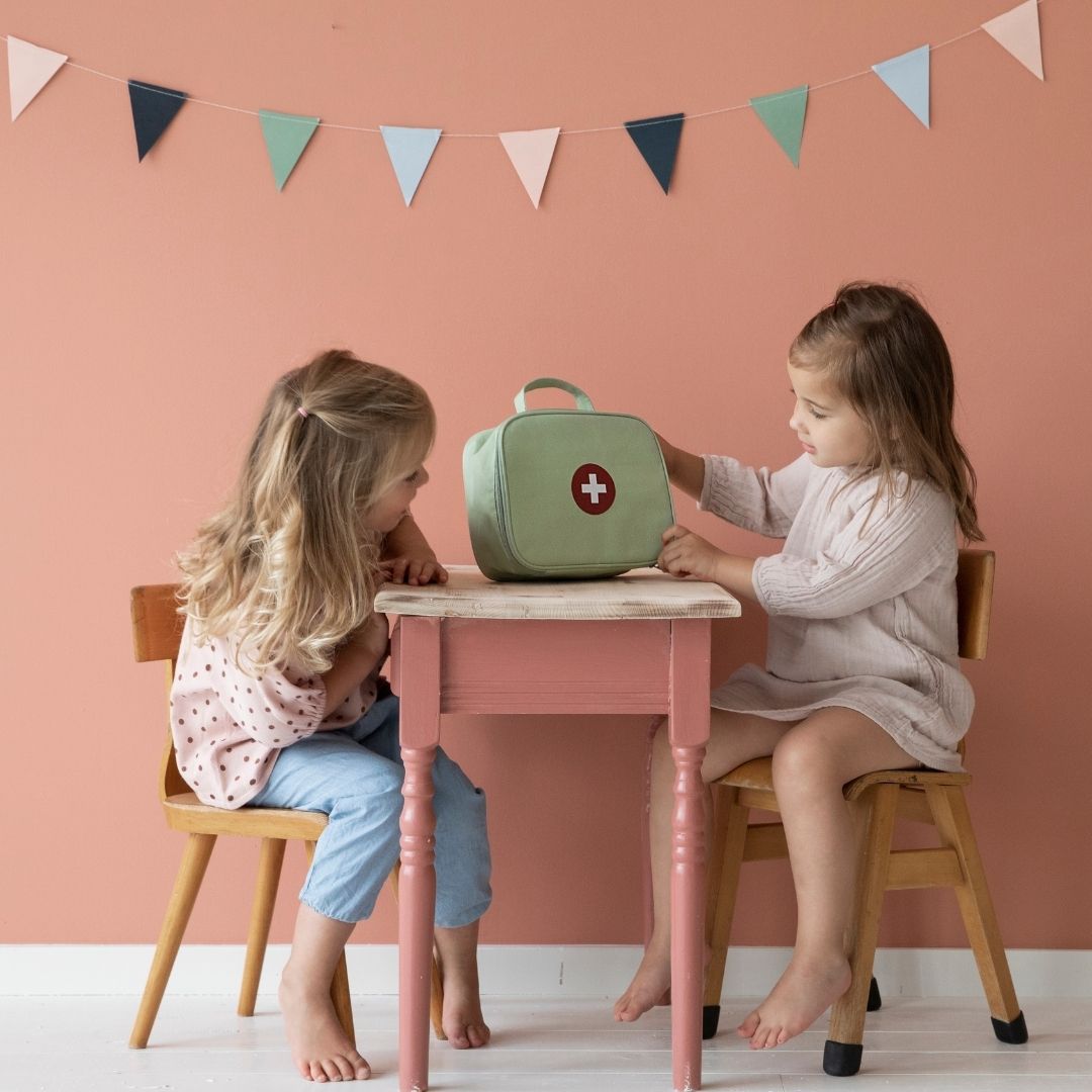 To piger ved bord ser på grøn lægetaske fra Little Dutch, fås hos Nordic Simply