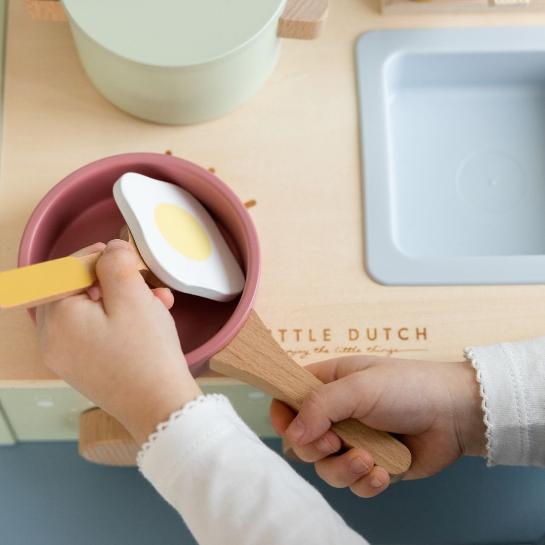 Barn tilbereder et spejlæg ved lille legekøkken i træ fra Little Dutch med kogeplader og vask, fås hos Nordic Simply.