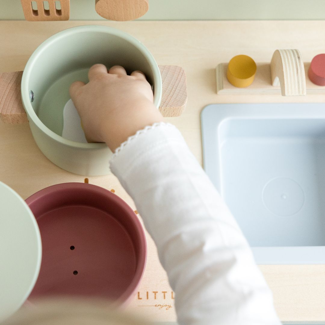 Barn tilbereder mad ved lille legekøkken i træ fra Little Dutch med kogeplader og vask, fås hos Nordic Simply.