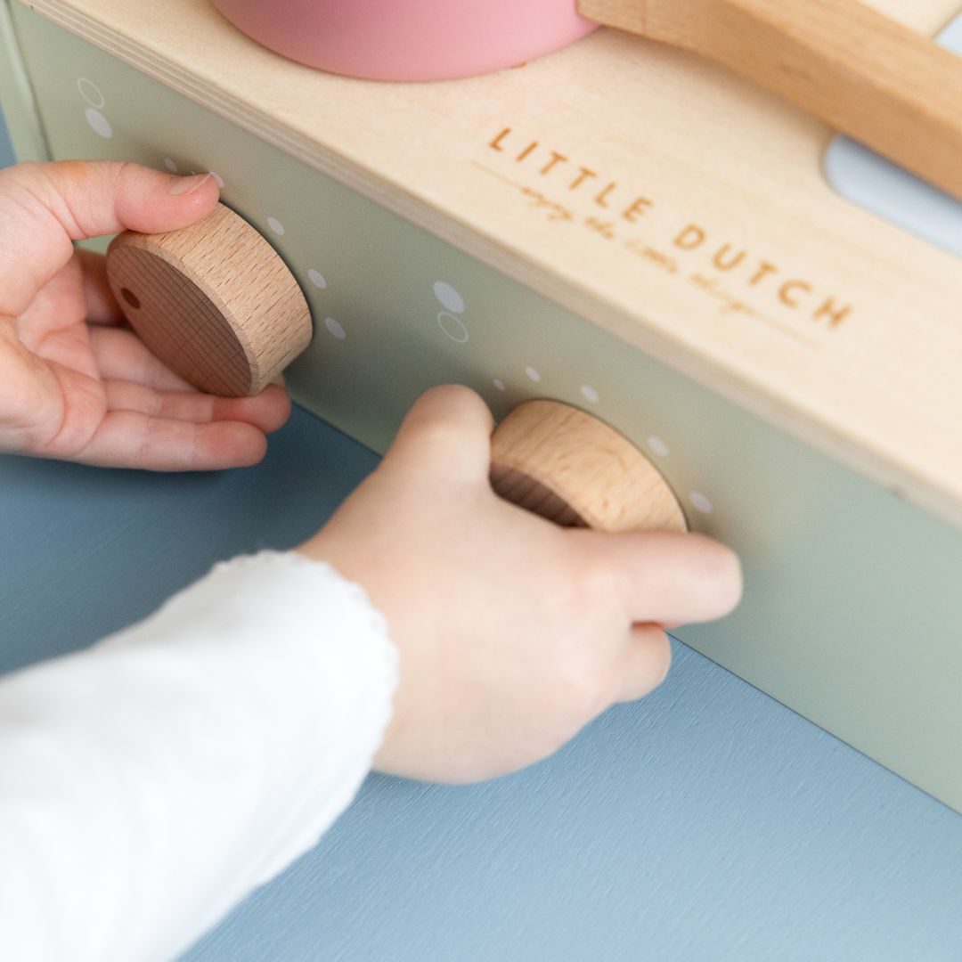Barn drejer knapper på lille legekøkken i træ fra Little Dutch med kogeplader og vask, fås hos Nordic Simply.