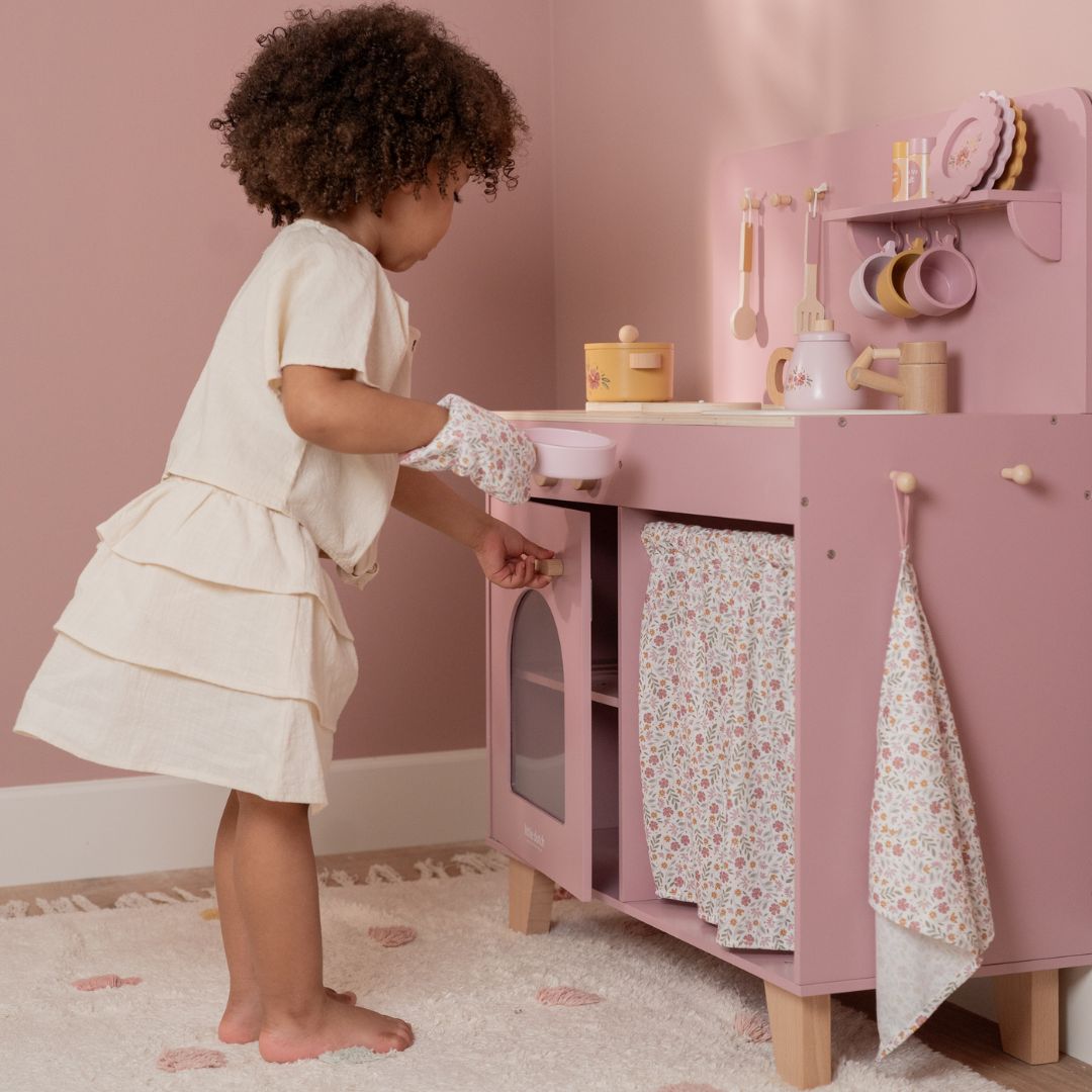 Legekøkken i rosa træ med tilbehør, her ses lille pige, der leger i pink køkken med udstyr