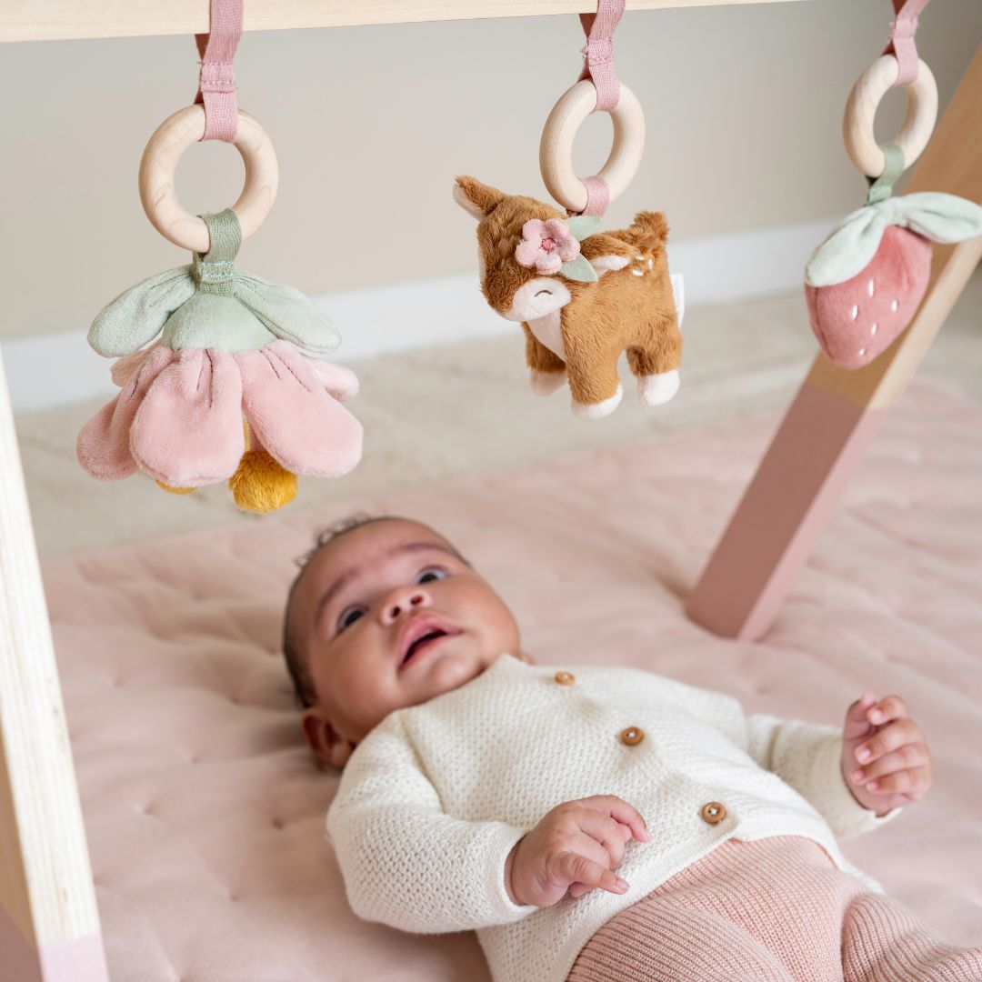 Baby der ligger på rosa legetæppe under aktivitetsstativ fra Little Dutch, fås hos Nordic Simply.