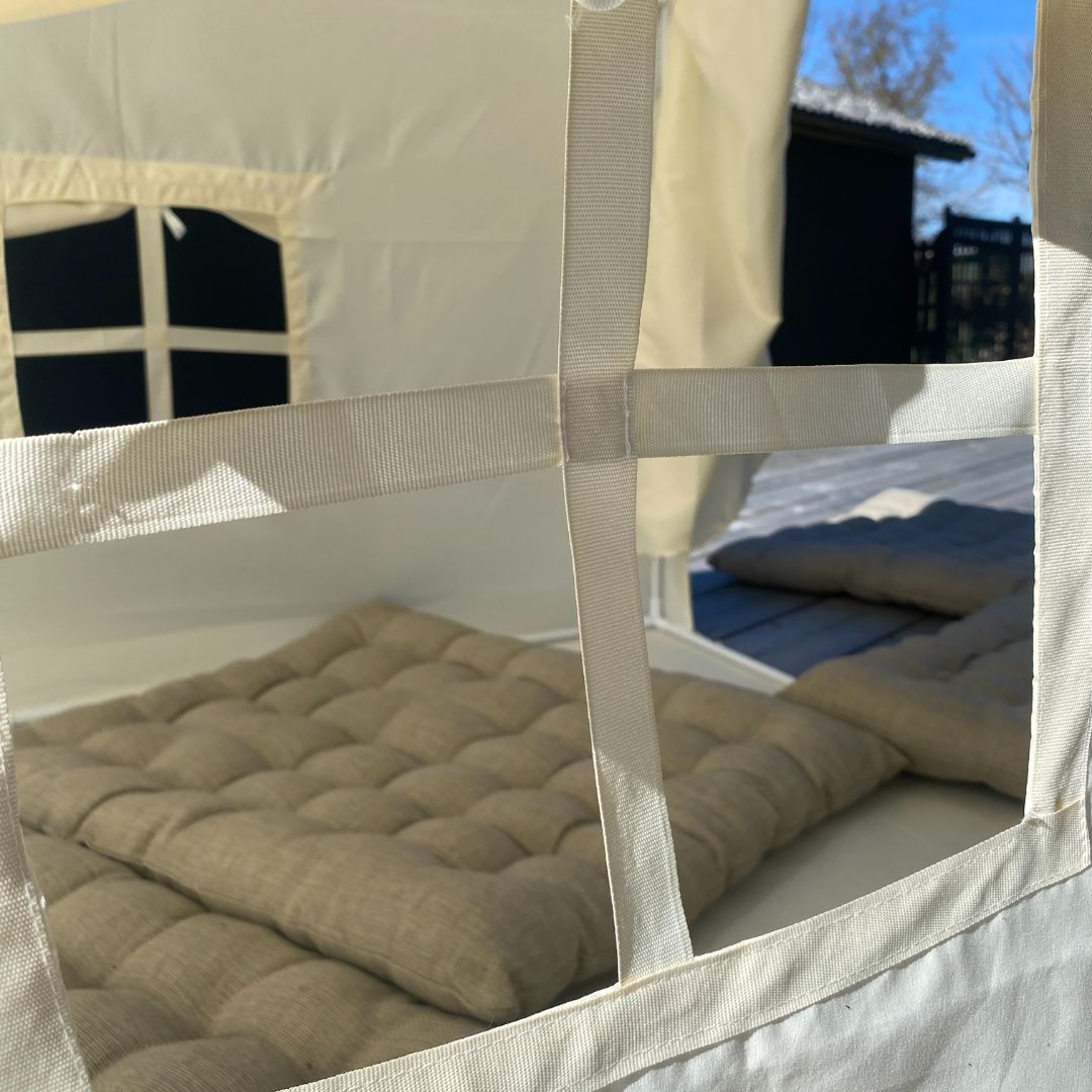 Legetelt stort, beige med stribet tag set indenfra med en blød madras og lys gennem vinduerne.