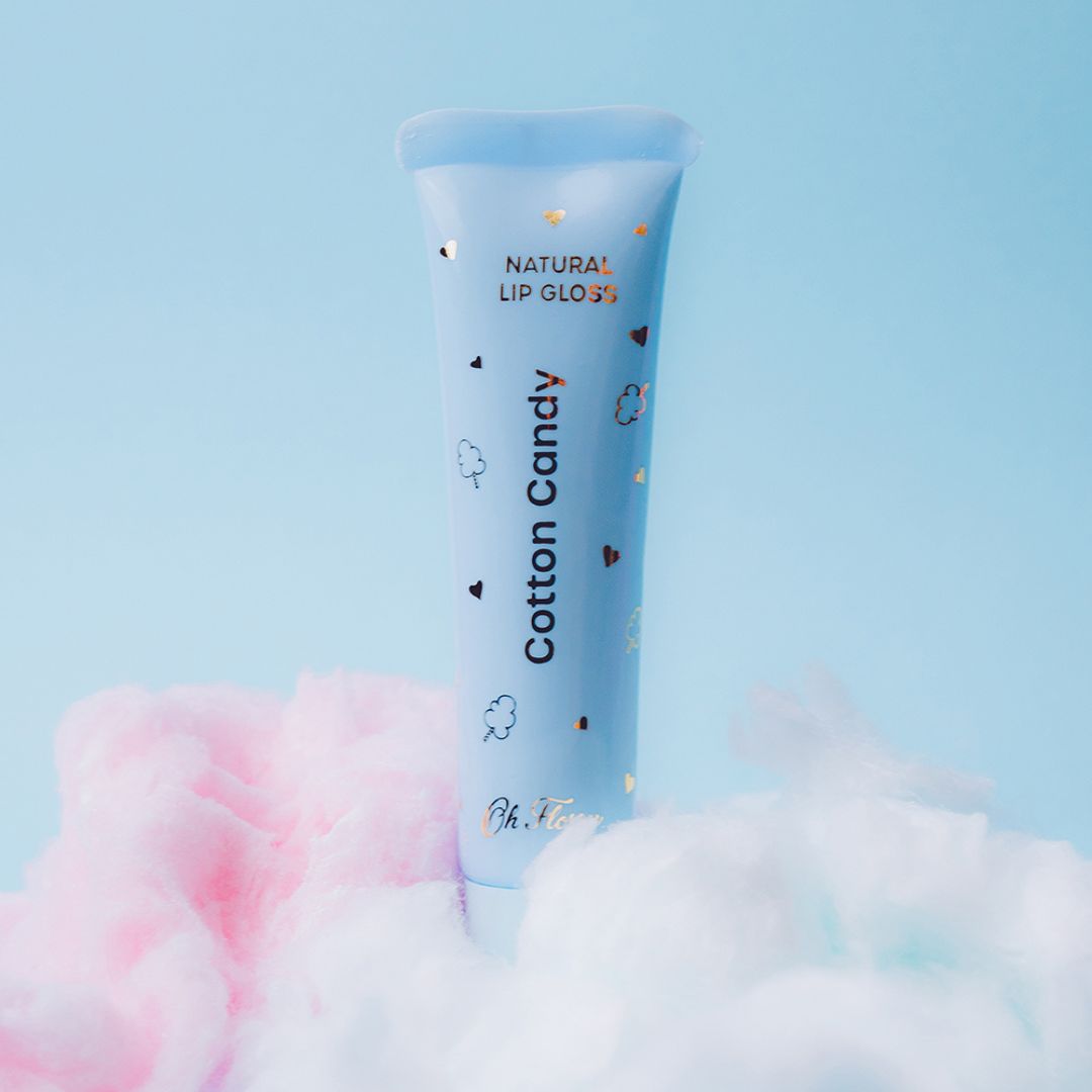 Blå tube med "candyfloss" lipgloss på blå baggrund med candyfloss nederst. Naturlig lip gloss til børn fra Oh Flossy Australien fås hos Nordic Simply