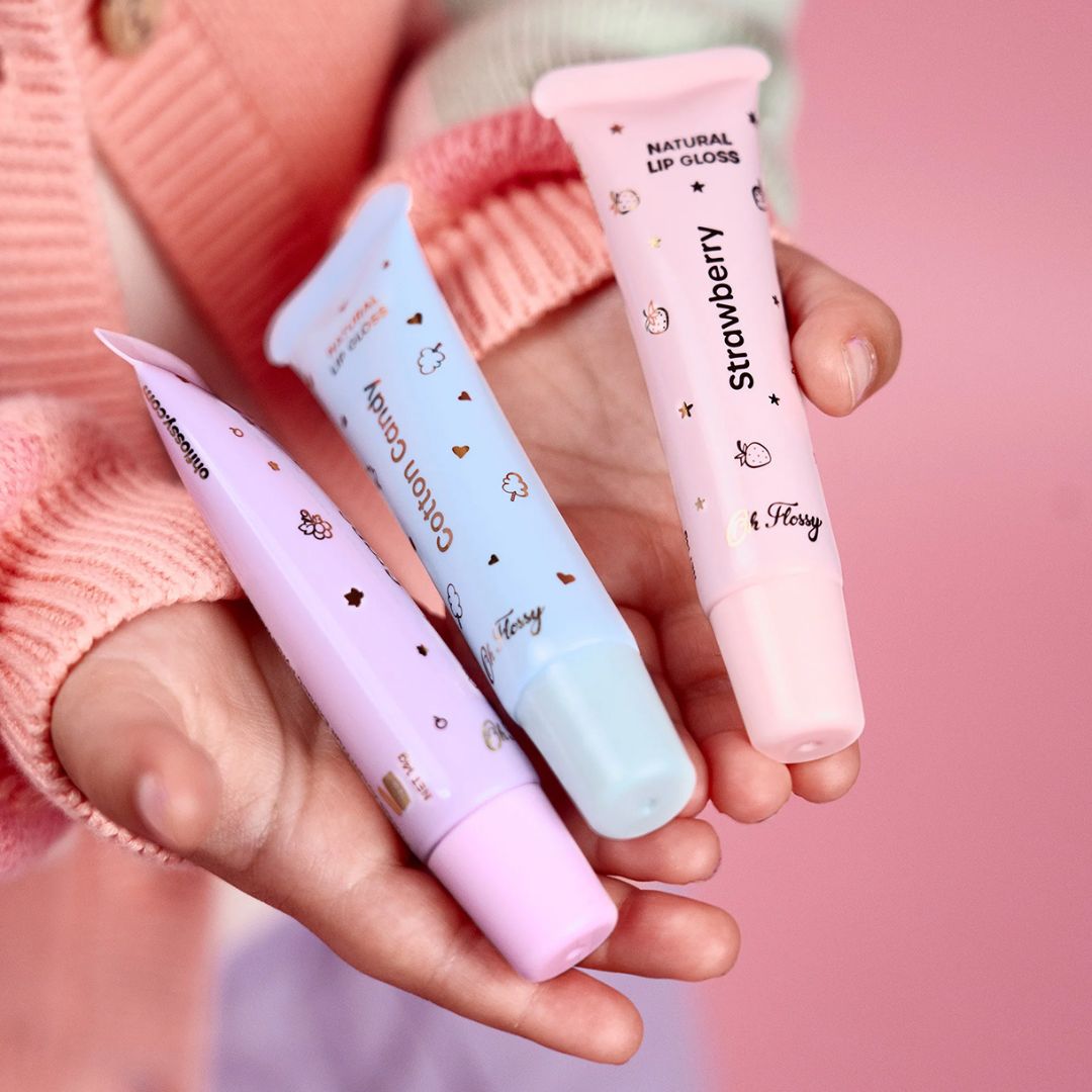 Hænder med 3 tuber naturlig lipgloss i lilla blå og rosa rosa fra Oh Flossy Australien fås hos Nordic Simply