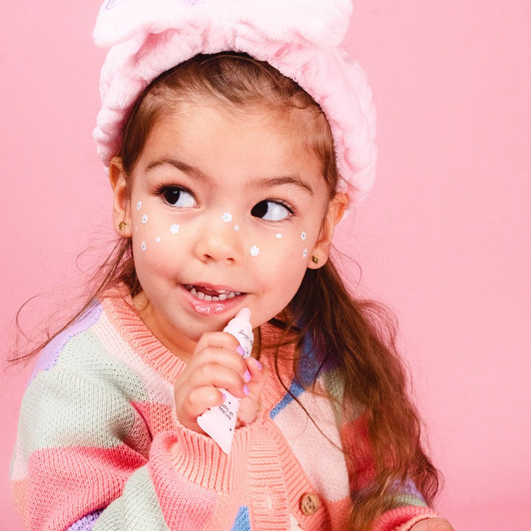 Pige smører lipgloss i rosa tube på læber. Naturlig lip gloss til børn fra Oh Flossy Australien fås hos Nordic Simply