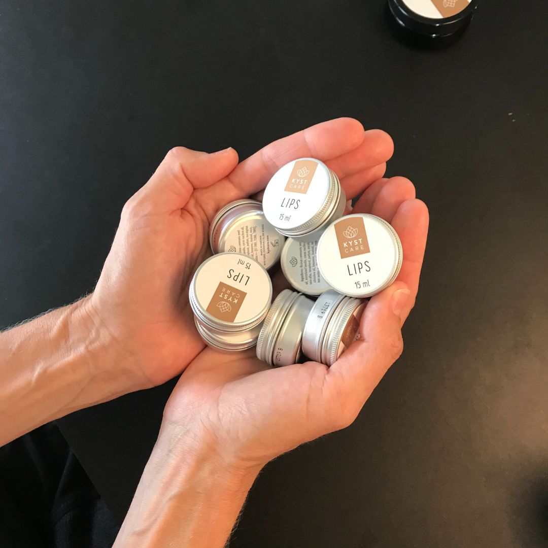Hænder med Lips rlæbepomade i små dåser, dansk hudpleje fra Kyst Care fås hos Nordic Simply