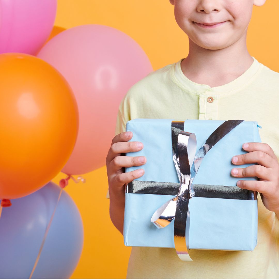 Dreng holder lyseblå gave til børnefødselsdag, kasse med blandede gaver til fødselsdag 6-9 år fås hos Nordic Simply