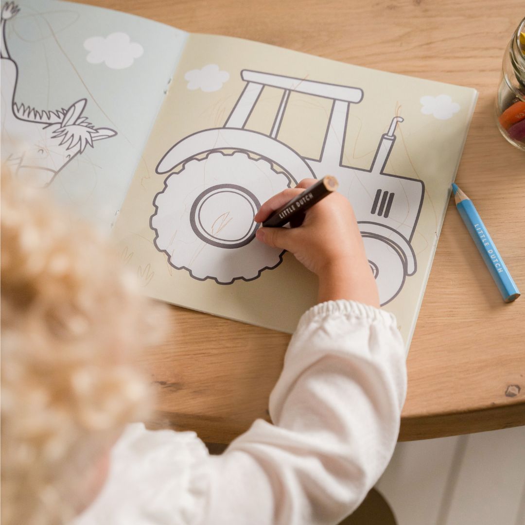 Barn tegner traktor i malebog med motiver af bondegården fra Little Dutch. God fra 2 år og op