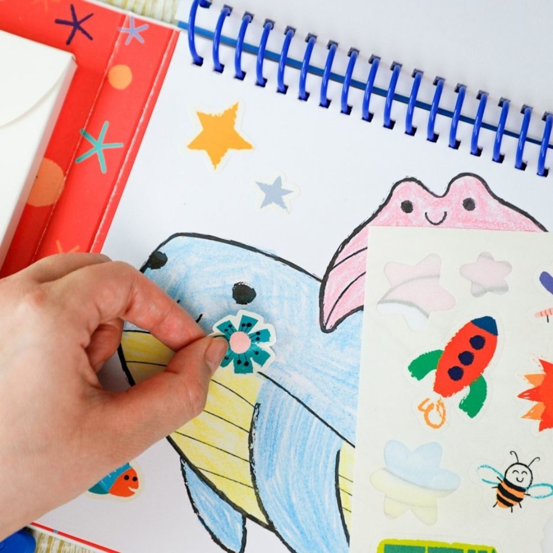 Barn der maler i "Mit første malesæt - Havet" bog med farver og klistermærker, ideelt fra 3 år og op fra Haku Yoka hos Nordic Simply