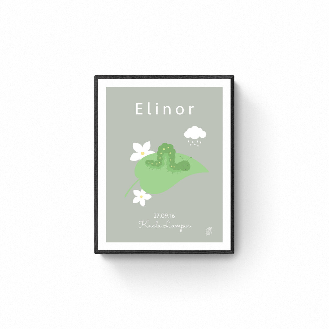 Grøn plakat med illustration af kålorm, og navnet Elinor, personlig plakat til barn med navn, fødselsdato og by, set i sort ramme på hvid væg, fra Nordic Simply