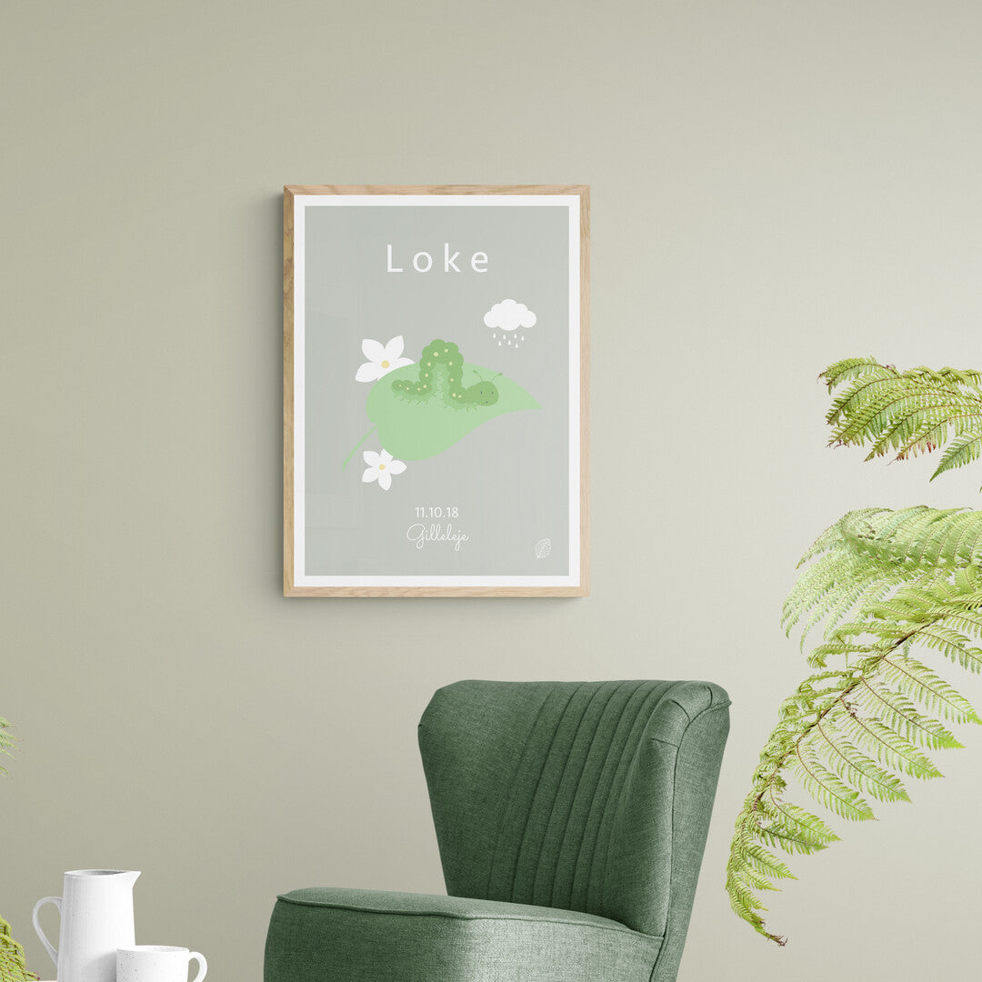 Grøn plakat med illustration af kålorm samt navnet Loke i hvide bogstaver, personlig plakat til barn med navn, fødselsdato og by, set i træramme på lys grøn væg, fra Nordic Simply