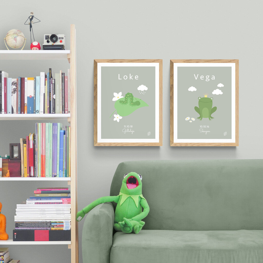 To grønne plakater, med kålorm og frø, til barn med navn, fødselsdato og by, hænger i trærammer på lys grøn væg i stue fra Nordic Simply