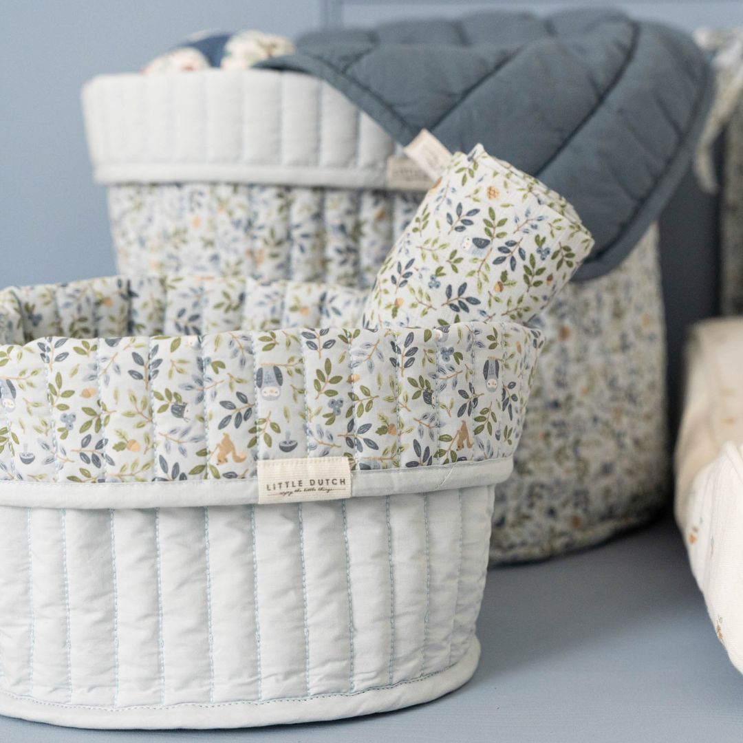 2 runde opbevaringskurve i lyseblå med blomstret ombukket kant, 1 stor kurv og 1 lille kurv med stofbleer ved pusleplads. Kurvene er quiltet i 100% økologisk bomuld og kan vendes. Fra Little Dutch Forest Adventure kollektion.