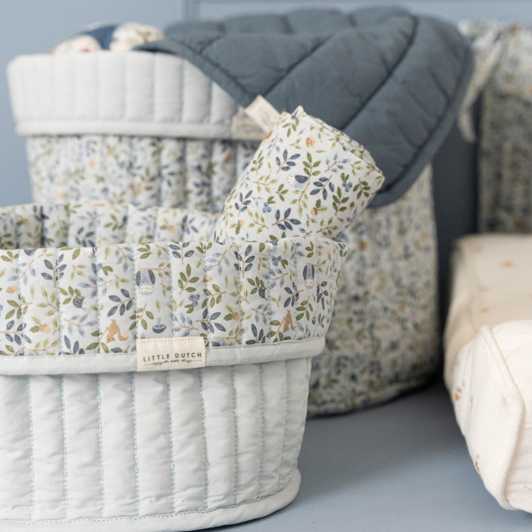 2 runde opbevaringskurve i lyseblå med blomstret ombukket kant, 1 stor kurv og 1 lille kurv med stofbleer ved pusleplads. Kurvene er quiltet i 100% økologisk bomuld og kan vendes. Fra Little Dutch Forest Adventure kollektion.