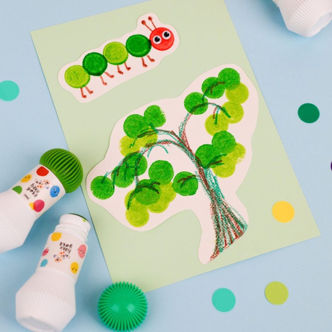 Farverige prikmarkører skaber sjove kunstværker med et grønt træ og en sød larve på papir.
