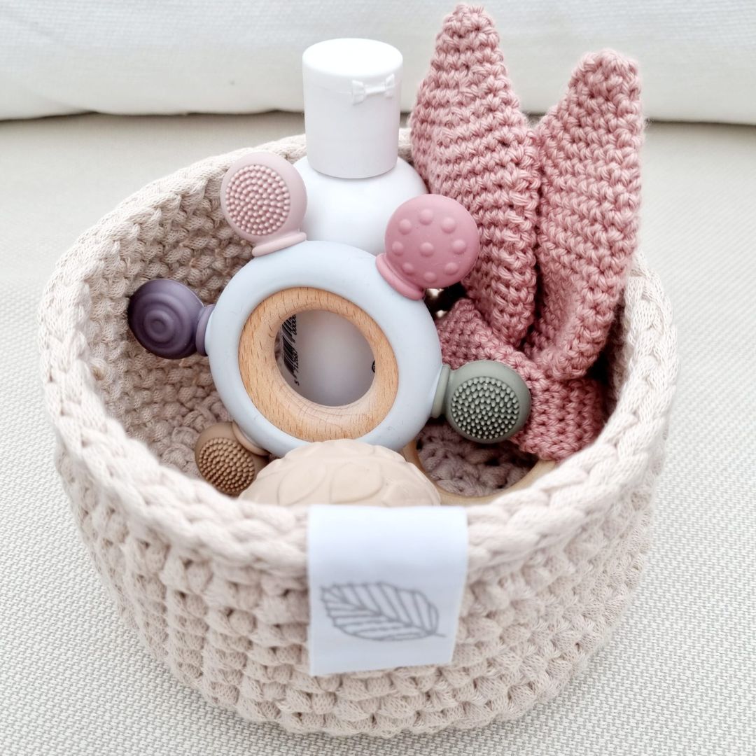 Lille rund puslekurv med baby produkter, kurven er en del af puslekurvesæt til med 3 håndlavede kurve i lys sand, fås hos Nordic Simply