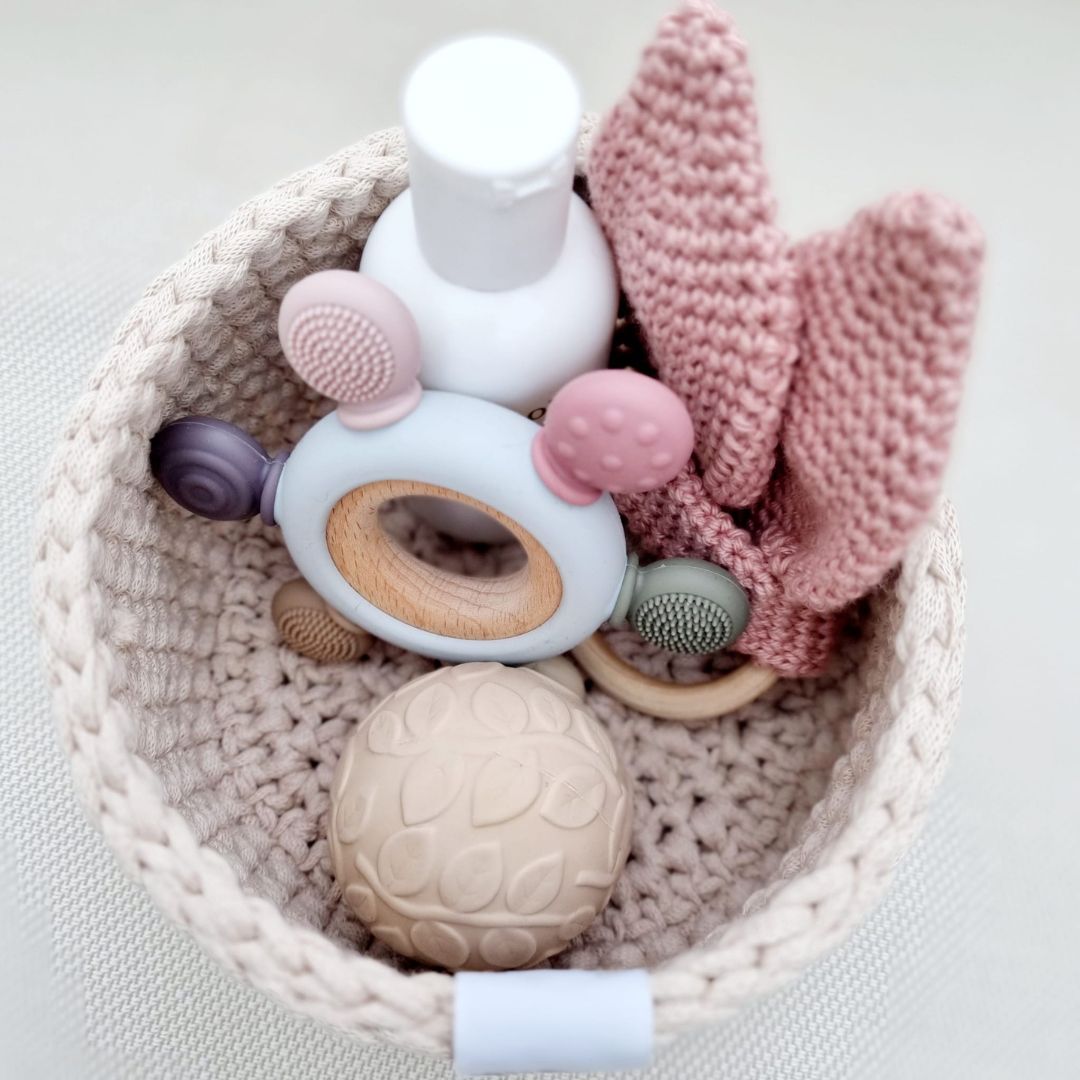 Lille rund puslekurv set oppefra med baby produkter, kurven er en del af puslekurvesæt til puslepladsen med 3 håndlavede kurve i lys sand, fås hos Nordic Simply