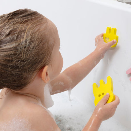 Barn sætter gule dyr i skum på badekar. Puslespil til badet fra Quut fås hos Nordic Simply
