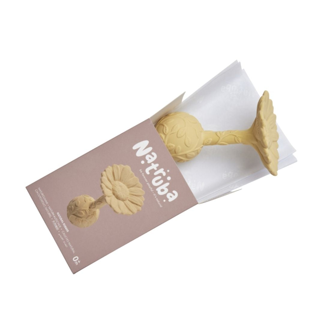 Gul rangle, formet som en marguerit med teksturer til baby, lavet i naturgummi af Natruba, set på vej ud af æske på hvid baggrund.