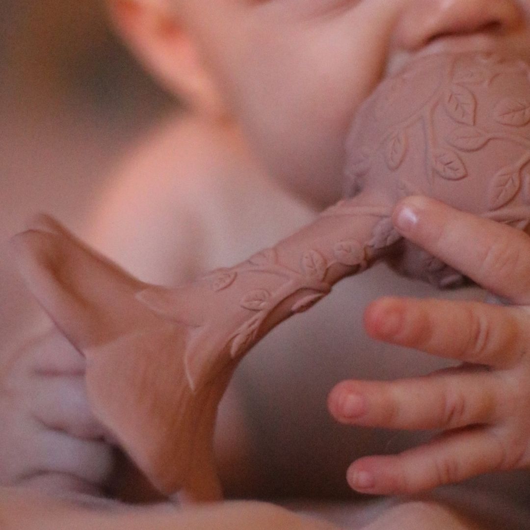 Baby med rosa rangle, formet som en plumeria med teksturer, naturgummi uden kemi fra Natruba.