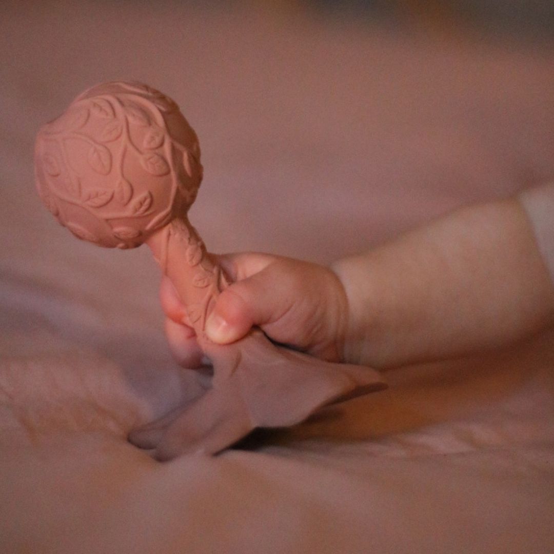 Hånd holder rosa rangle, formet som en hawaii-blomst med teksturer, fra Natruba, fås hos Nordic Simply