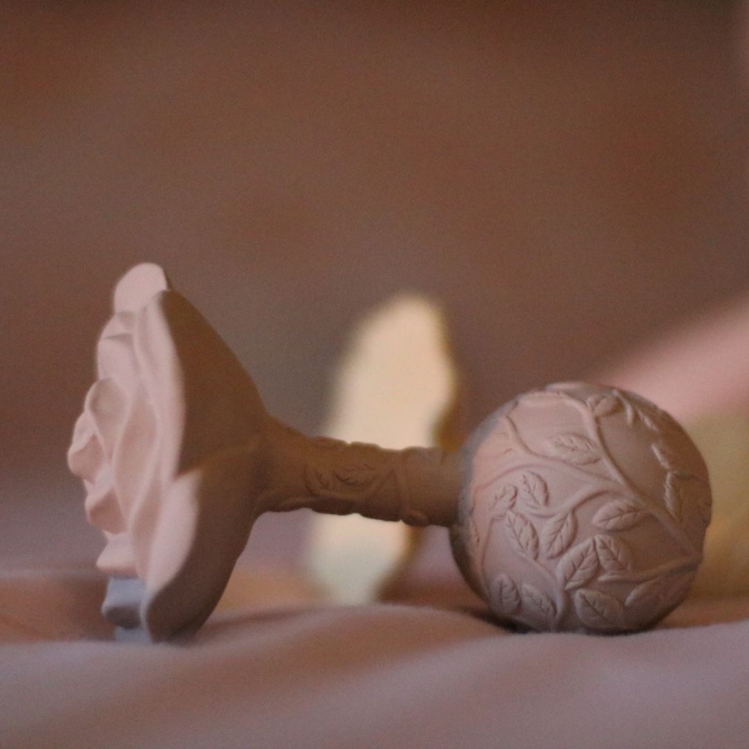 Beige rangle og bidering i et, formet som en rose, ligger på sengetæppe