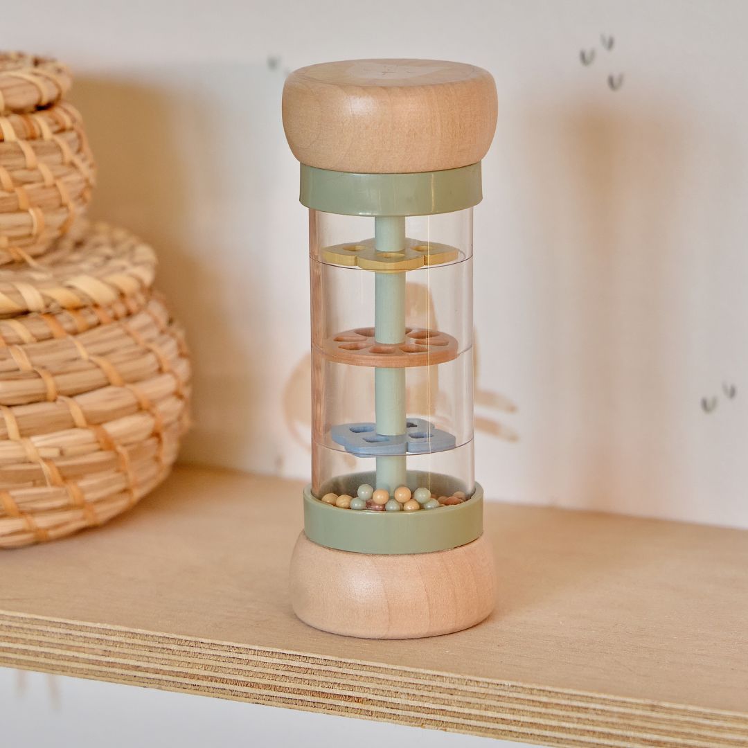 regnmager til baby med træ i enderne og grønne detaljer med safaritema, set på hylde i træ i børneværelse.