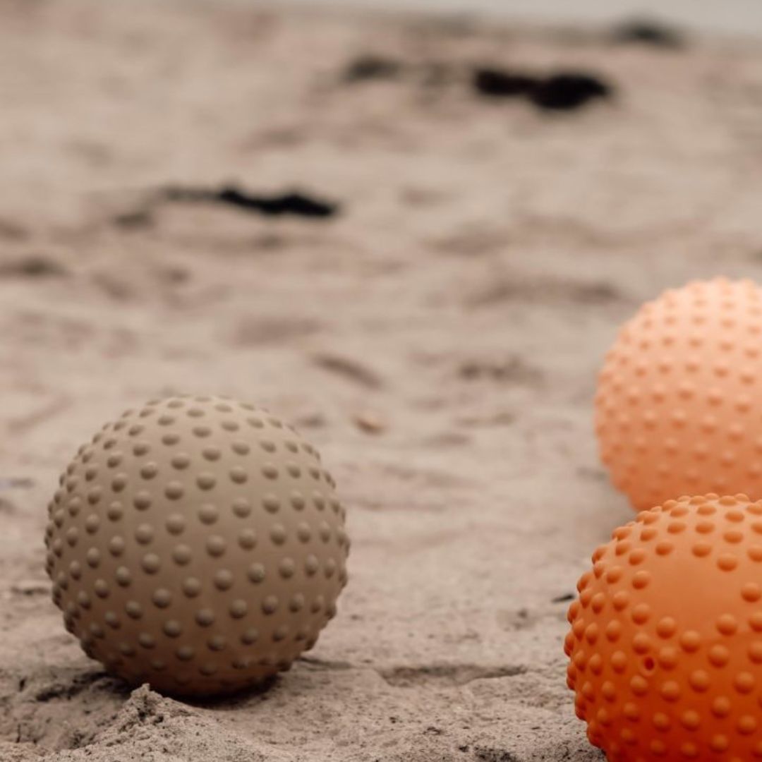 Farverige sansebolde med knopper set på strand, perfekt til leg og sansestimulation for børn.