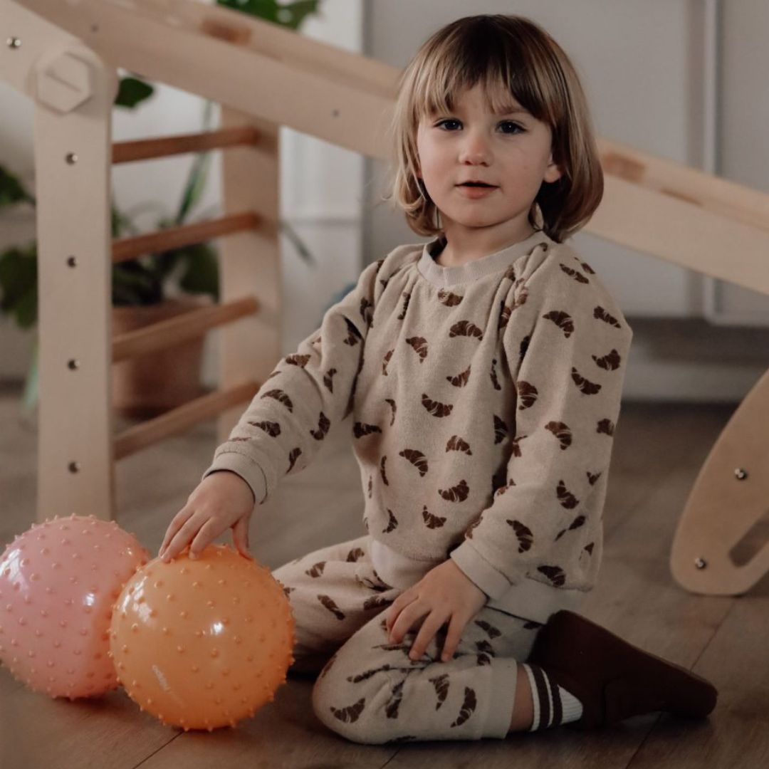 barn sidder i stue med to store sansebolde fra Find that Hippo i gul og rosa.